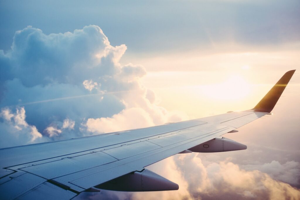 Airplane Flying Above Clouds Sunset - Travel Meadow Guide